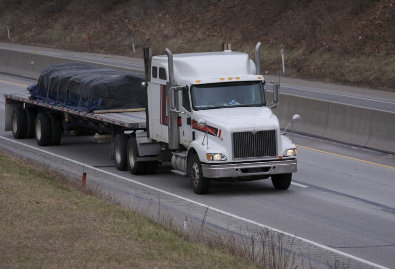 A tractor hauls a fltabed trailer and its load. t(Photo credit: Shutterstock)