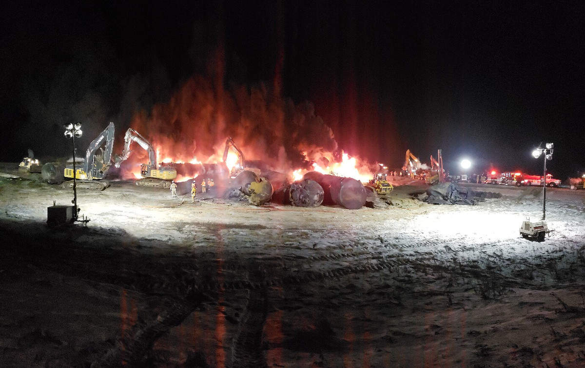 A photograph of fire burning next to some tank railcars. The photo was taken at night.