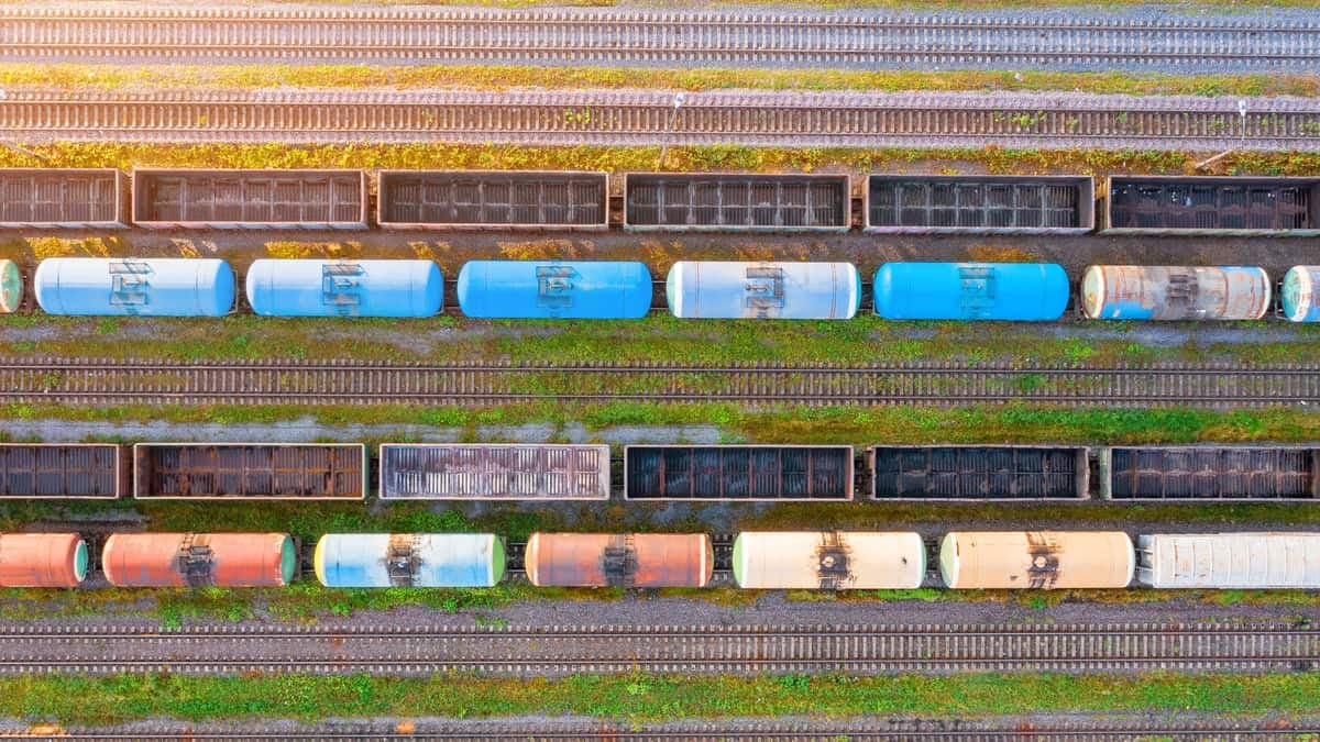 A photograph showing two rows of tank cars and two rows of empty railcars.