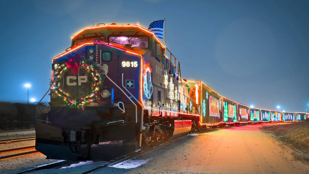 A photograph of a train at night. The train is decorated with Christmas lights and holiday decorations.