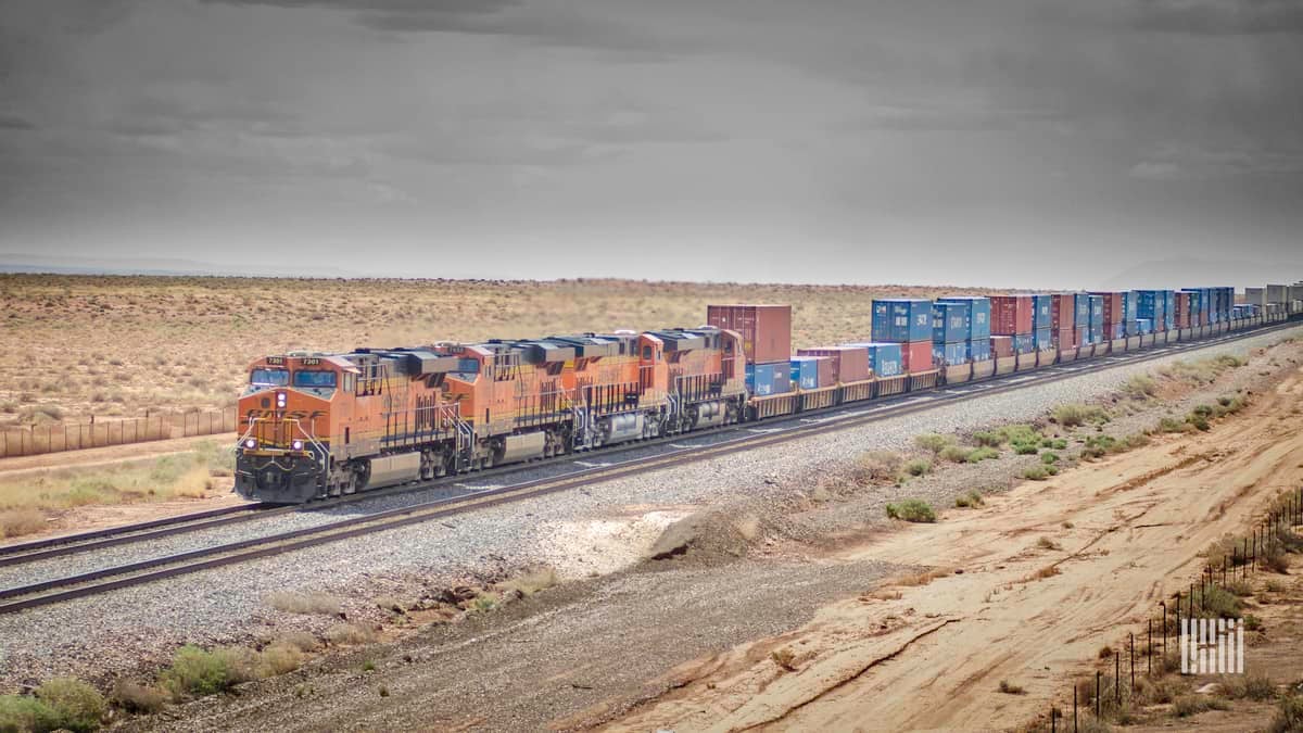 A locomotive is hauling container boxes through a field.