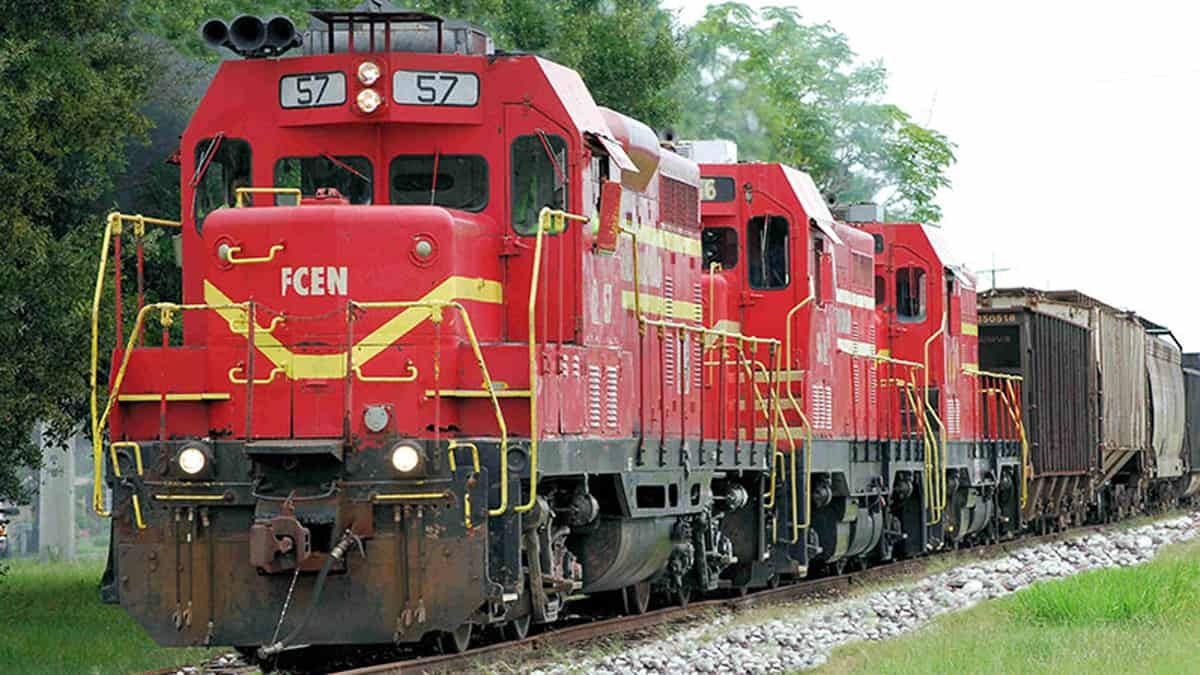 A photograph of a locomotive pulling two other locomotives and railcars,