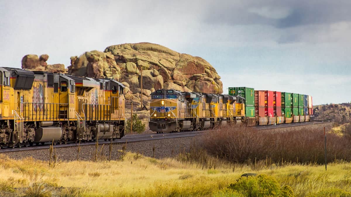 Two locomotives face each other on opposite tracks. One locomotive is hauling intermodal containers behind it.