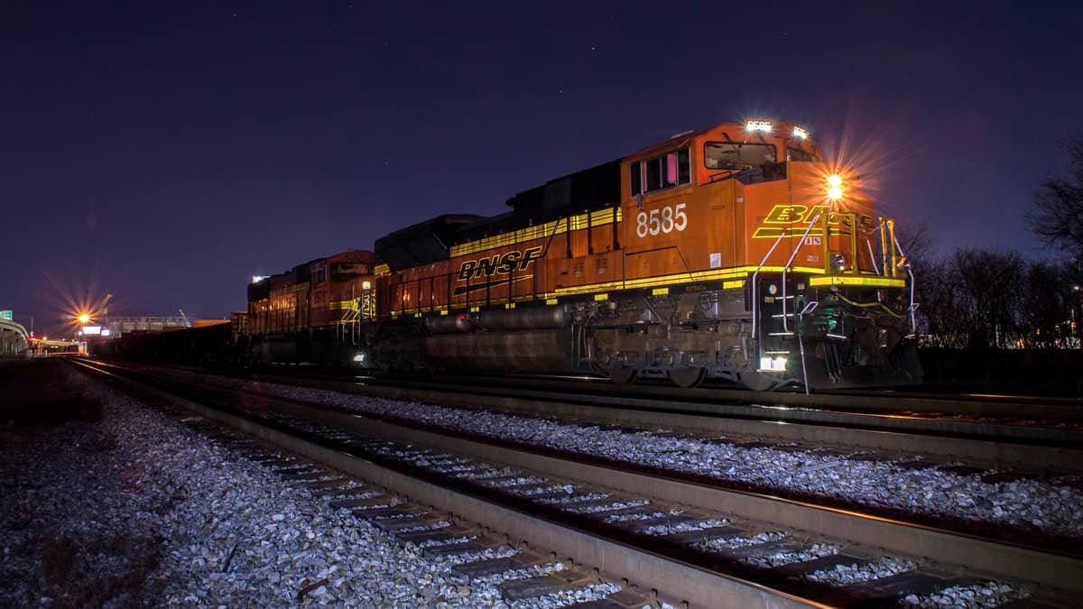 A photograph of a train on a rail track at nighttime.