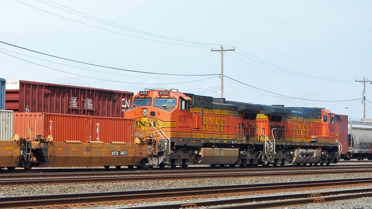 A photograph of a locomotive on a railway track. Intermodal containers are surrounding the locomotive.