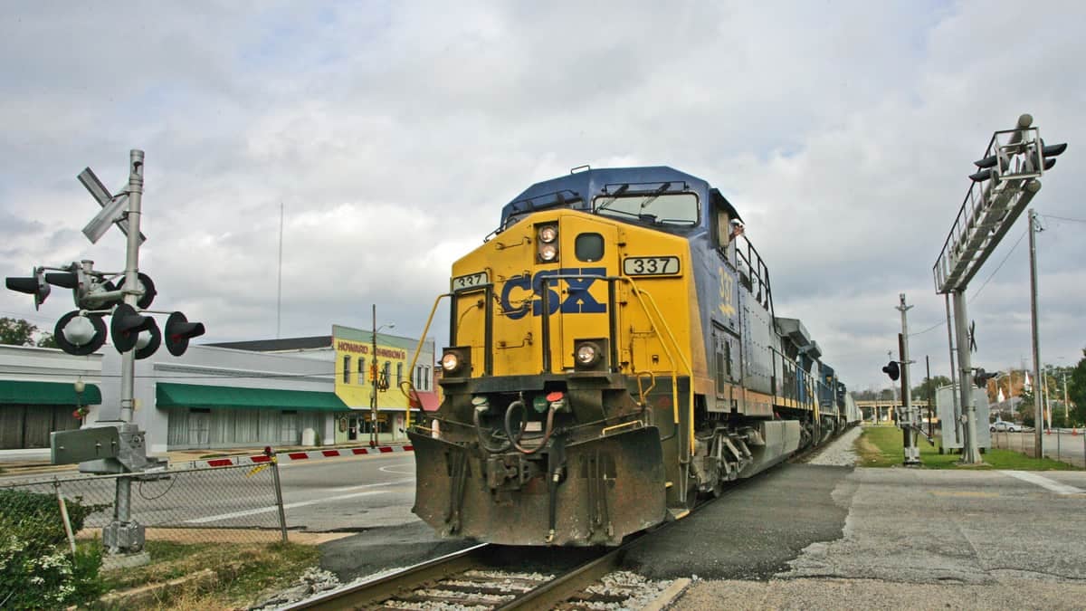 A photograph of a train passing a rail crossing.