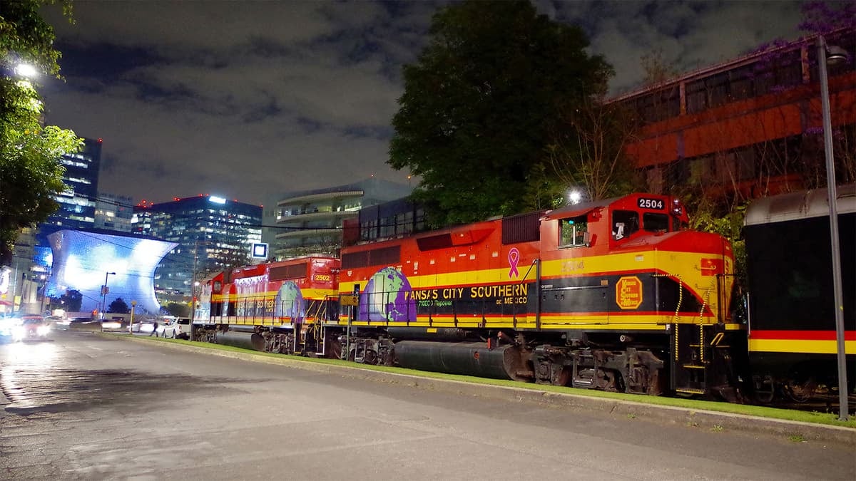 A photograph of a train traveling through a town at night.