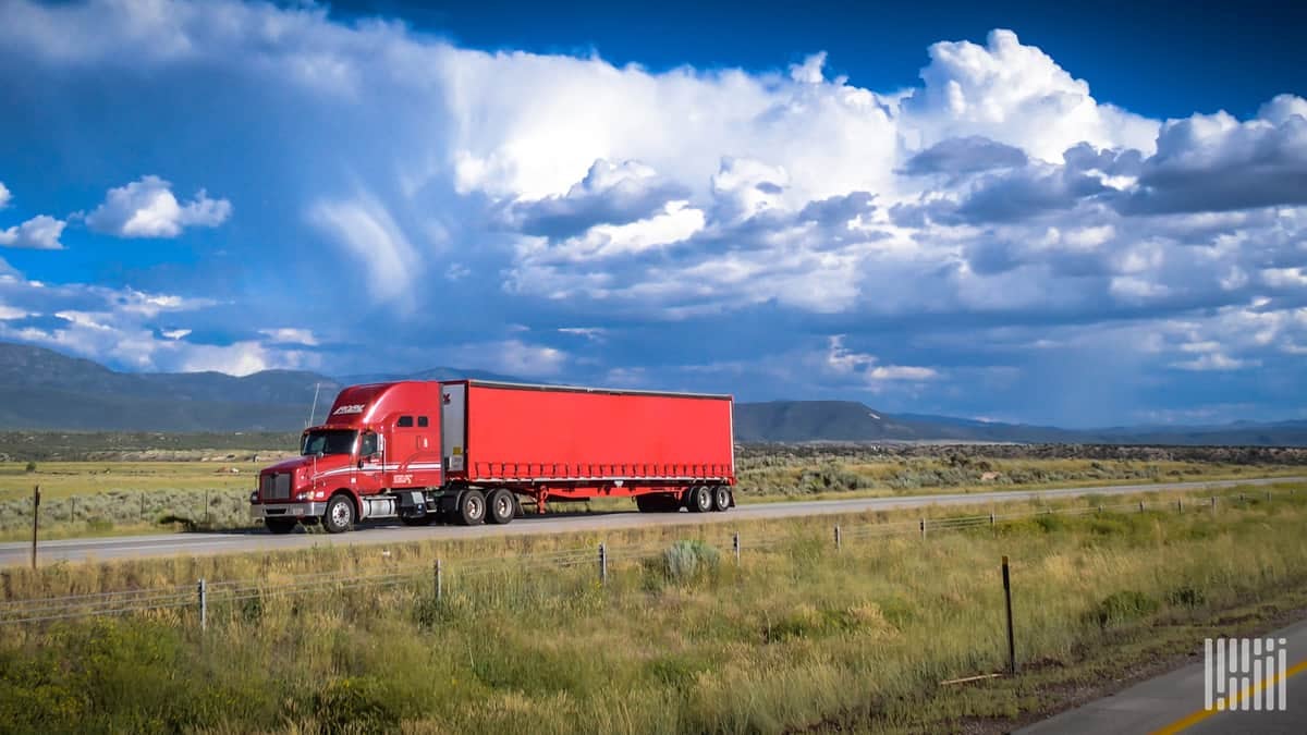 Red truck drives on highway in mountainous region