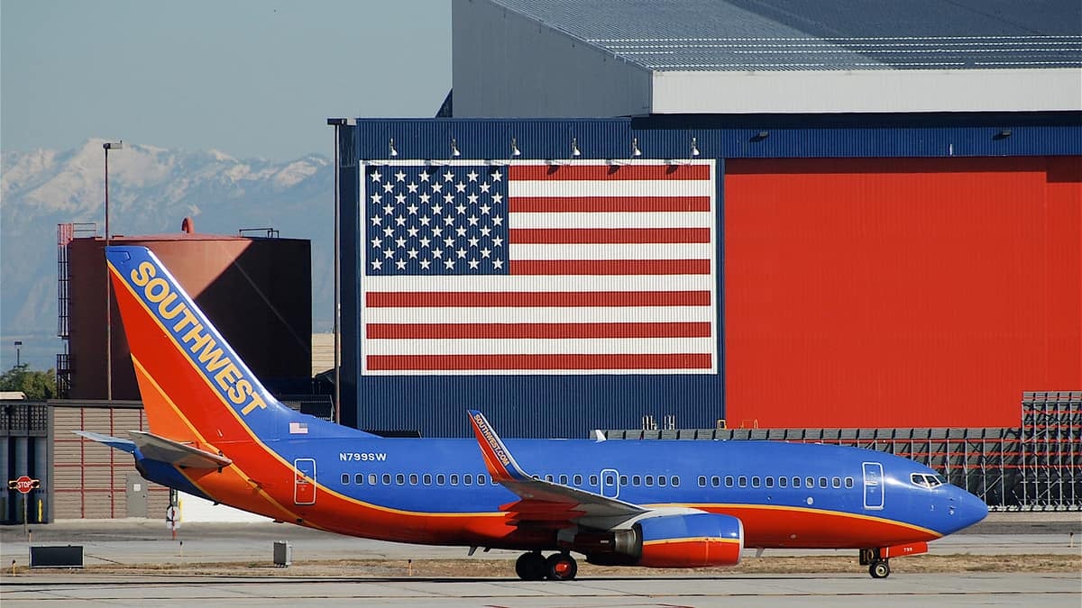 Blue/orange plane beneath a giant American flag.