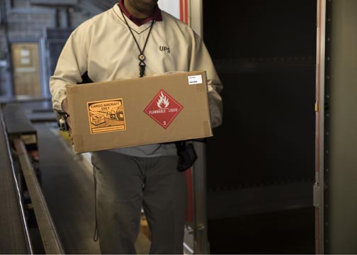 Warehouse worker holding box with a hazmat label on it