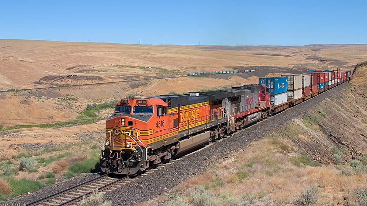 A photograph of a train pulling intermodal containers across a field.