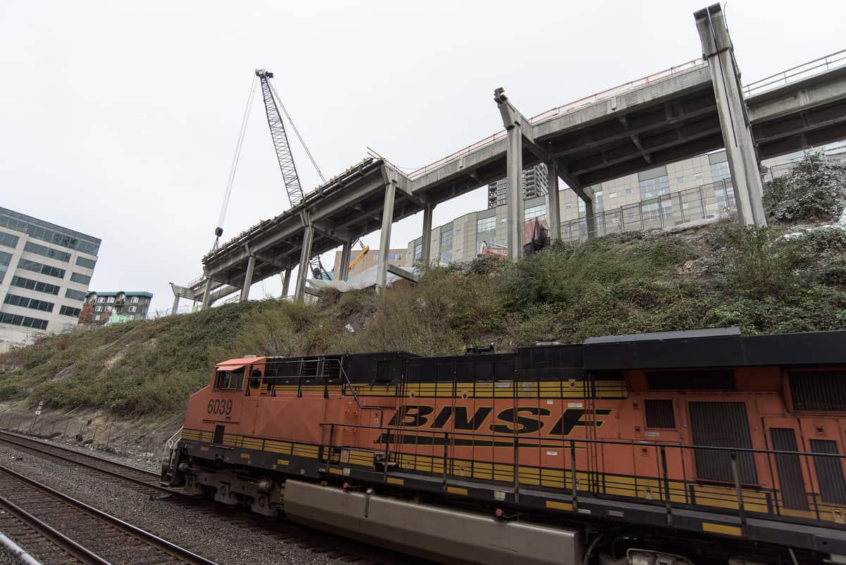 A photograph of a train locomotive traveling next to a construction site.