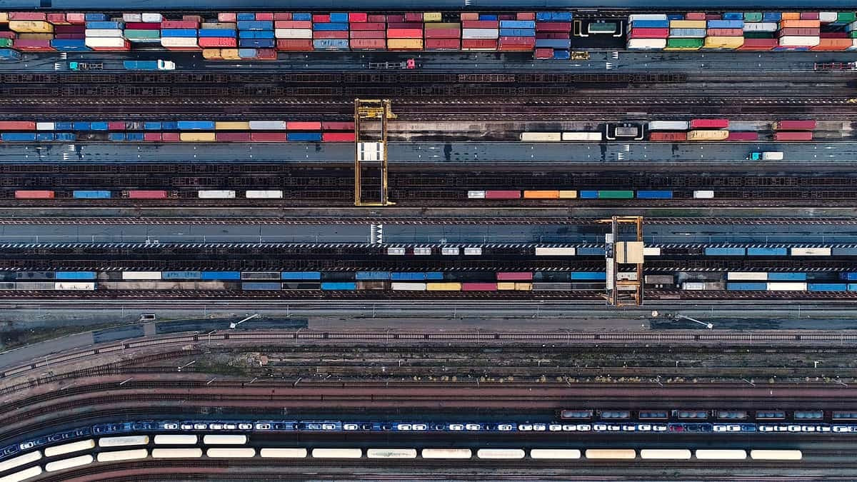 A photograph of an aerial view of a rail yard. There are rows of intermodal containers and railway track.