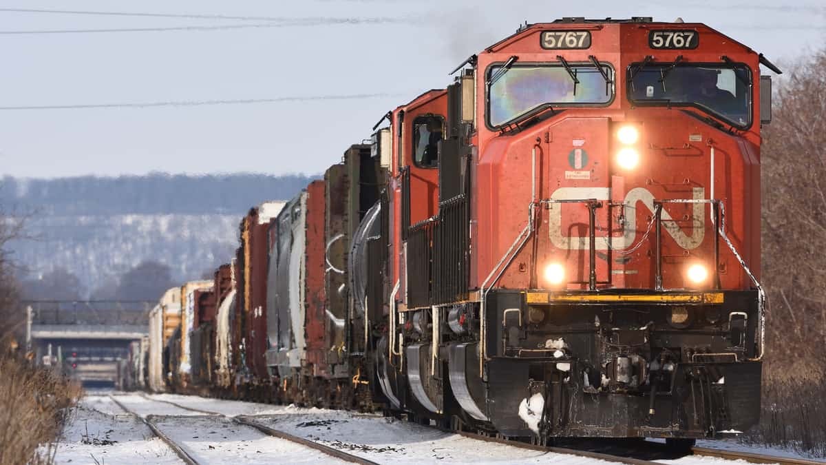 A photograph of a train traveling on a track. There is snow on the ground.