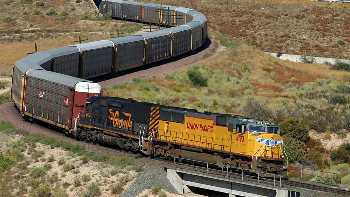 A photograph of a locomotive hauling a line of railcars in a grassy field.