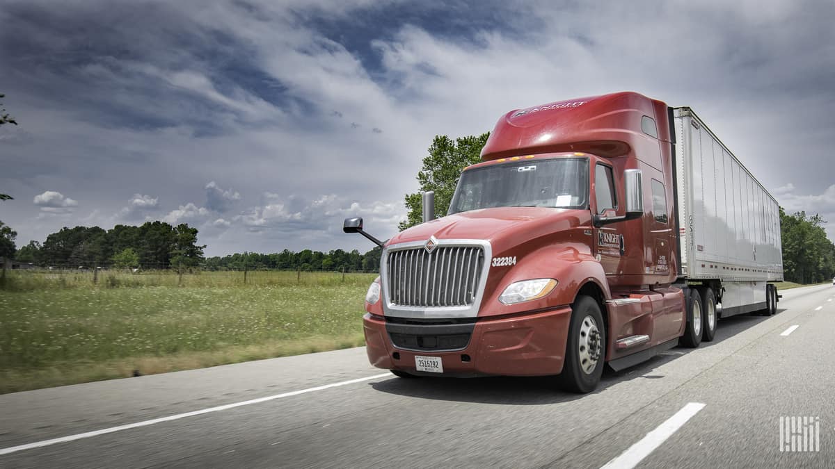 Red truck driving on highway in rural area