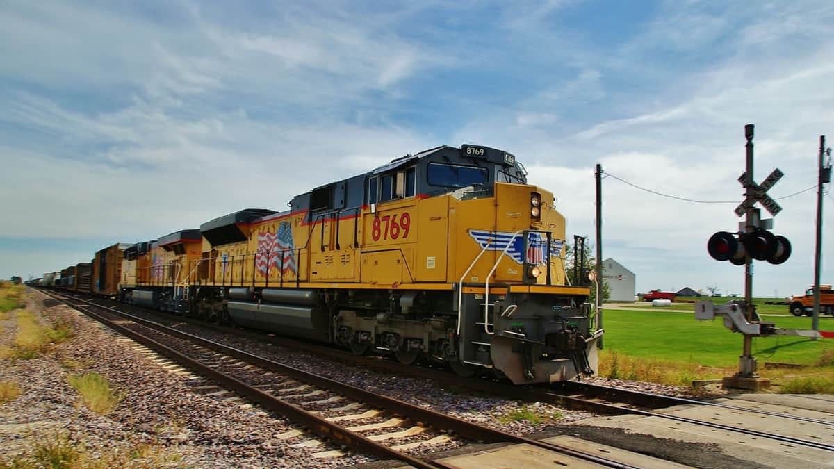 A photograph of a train near a railroad crossing.