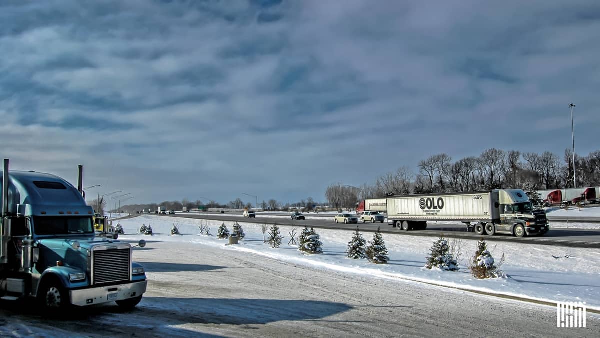 Tractor-trailers heading down a snowy road.