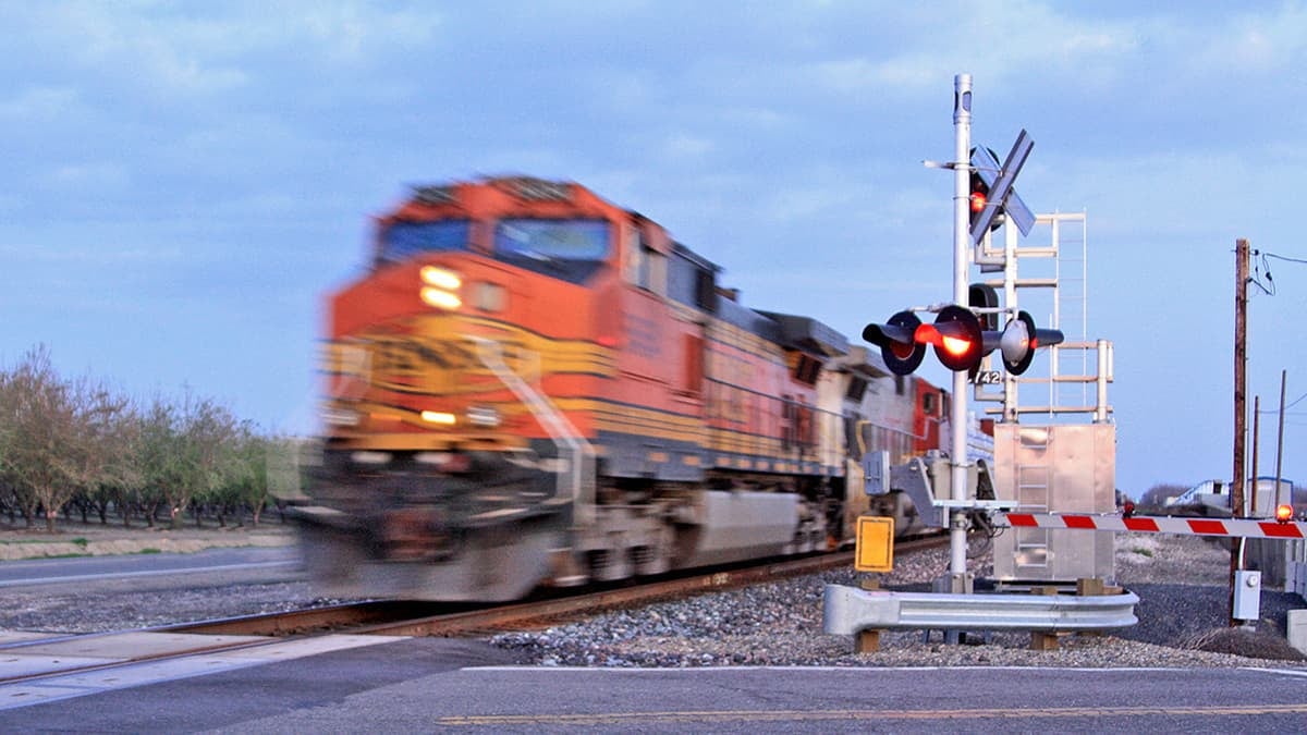 A photograph of a train at grade crossing.