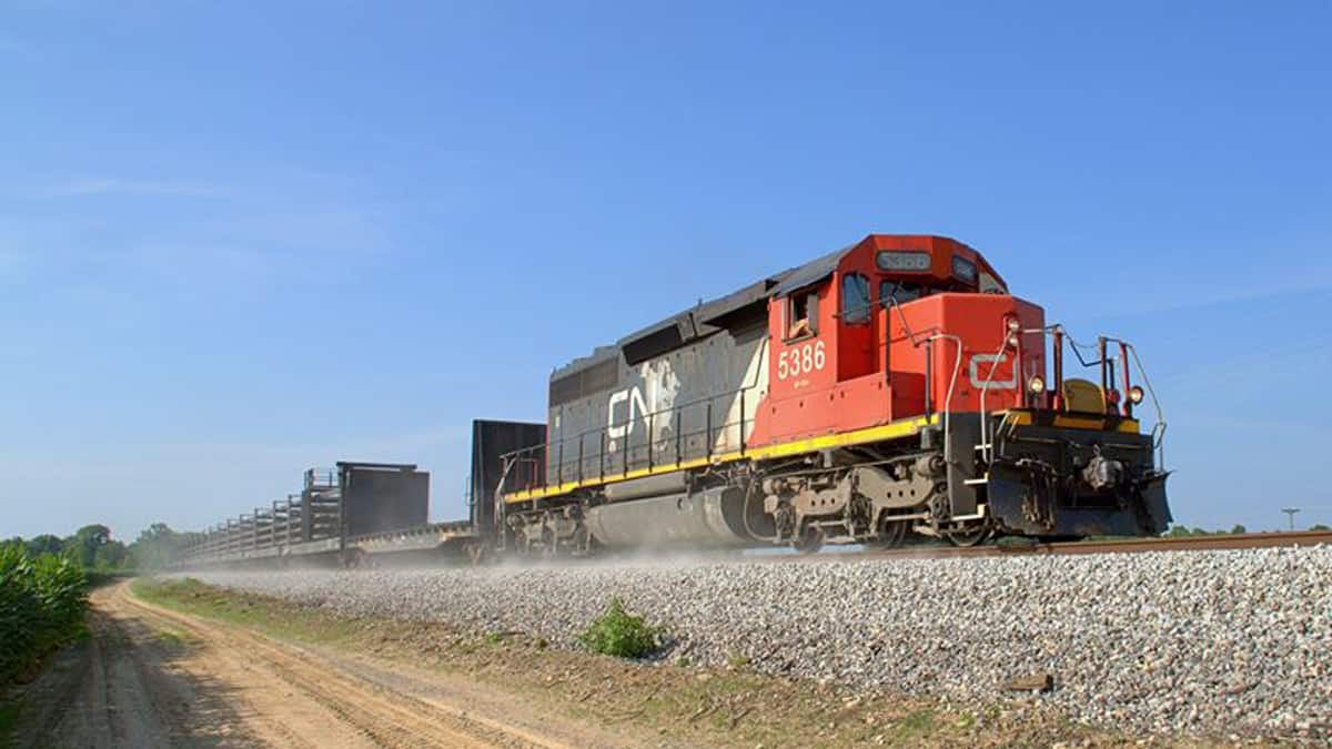 A photograph of a train traveling down a dirt field.