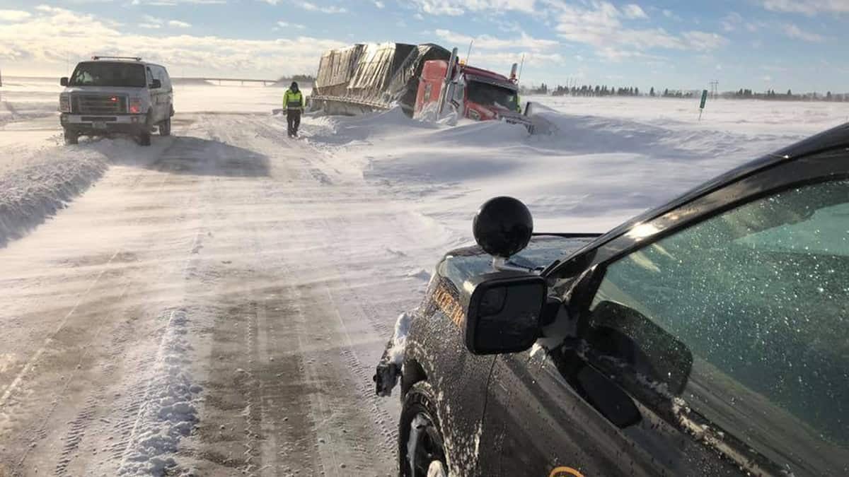 Flatbed truck stuck on side of snowy North Dakota road.