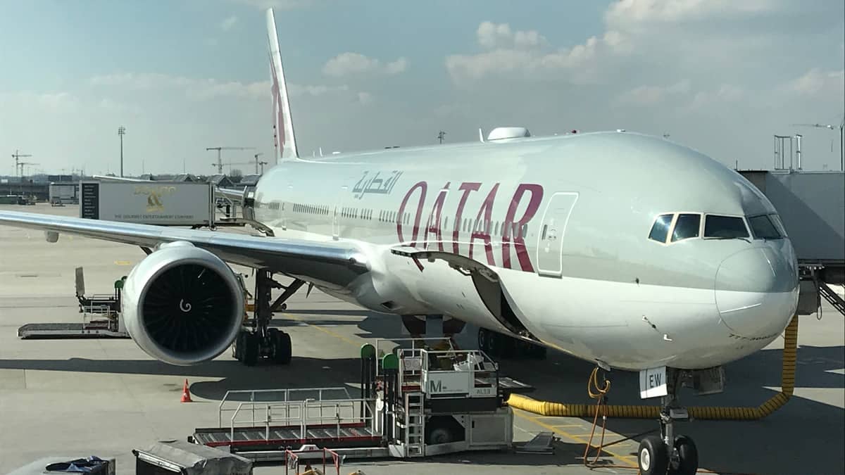 Large, gray Qatar Airways at airport gate.