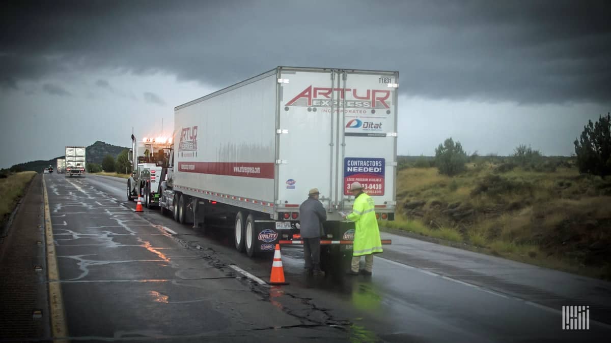 Tractor-trailer stopped on wet highway.