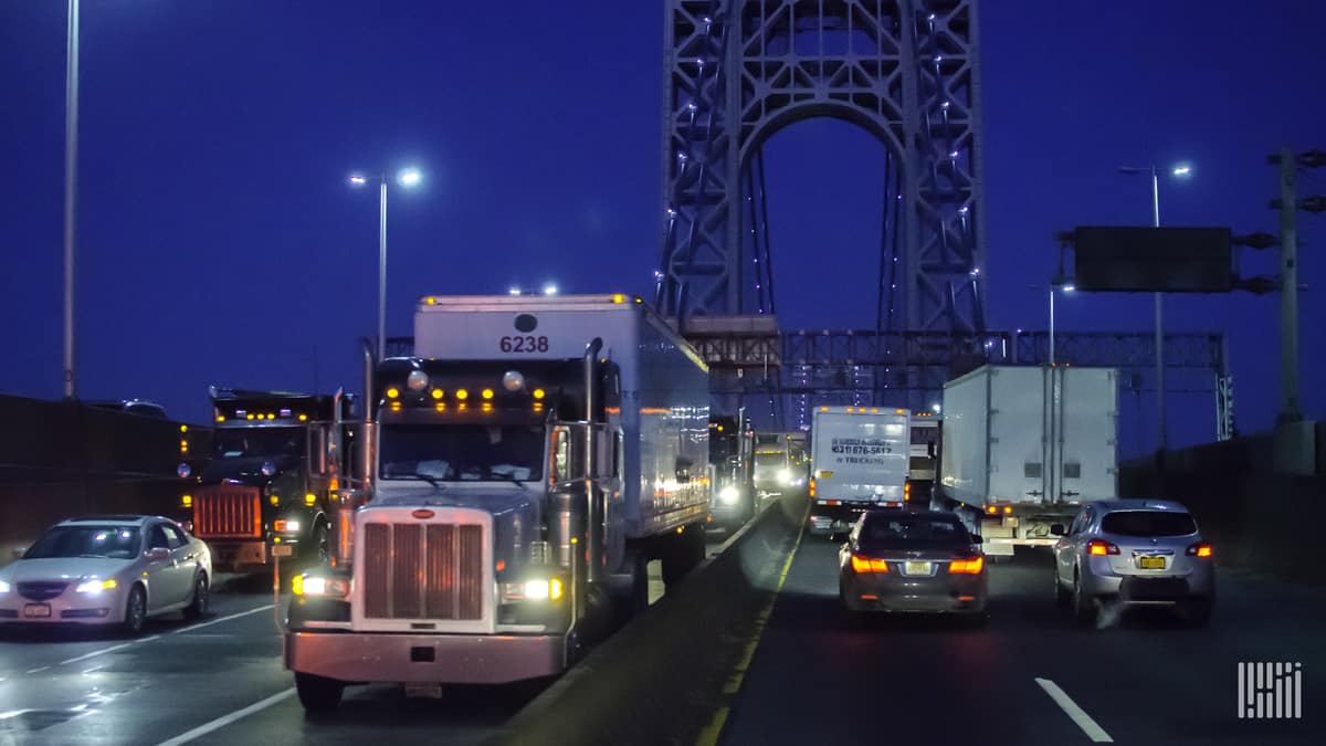 Tractor-trailers heading down wet road.