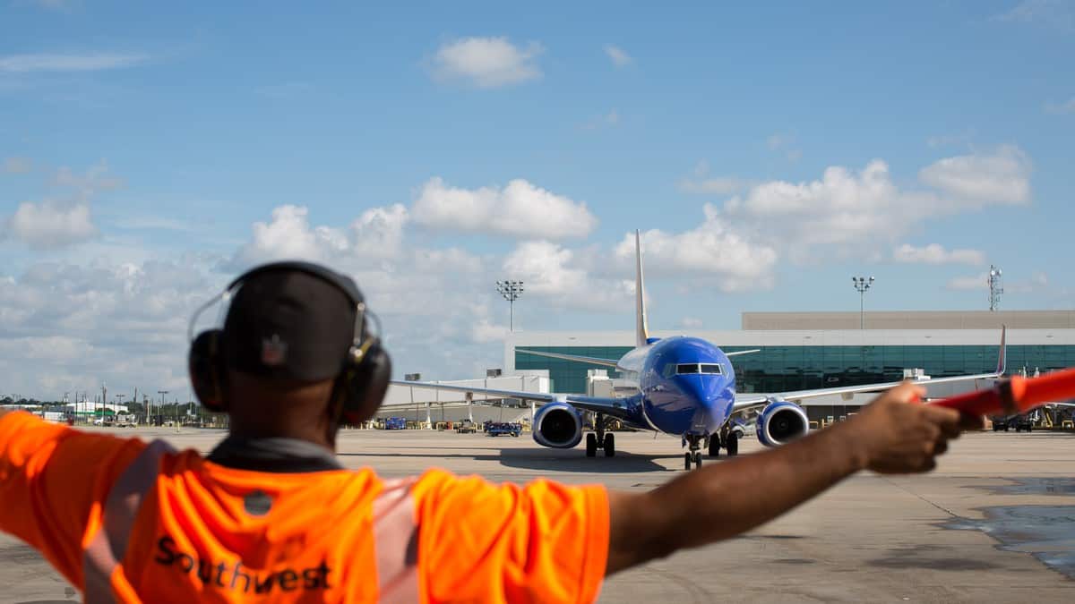 Southwest ground worker directs a plane where to go.