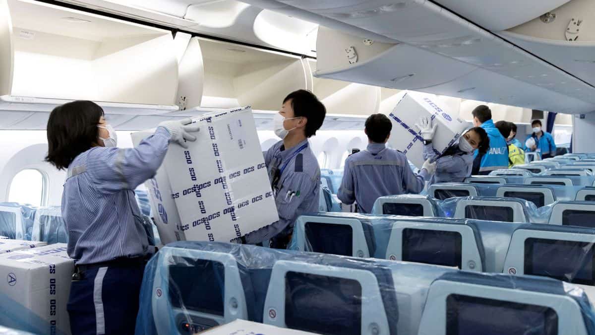 Workers put boxes in airline seats.