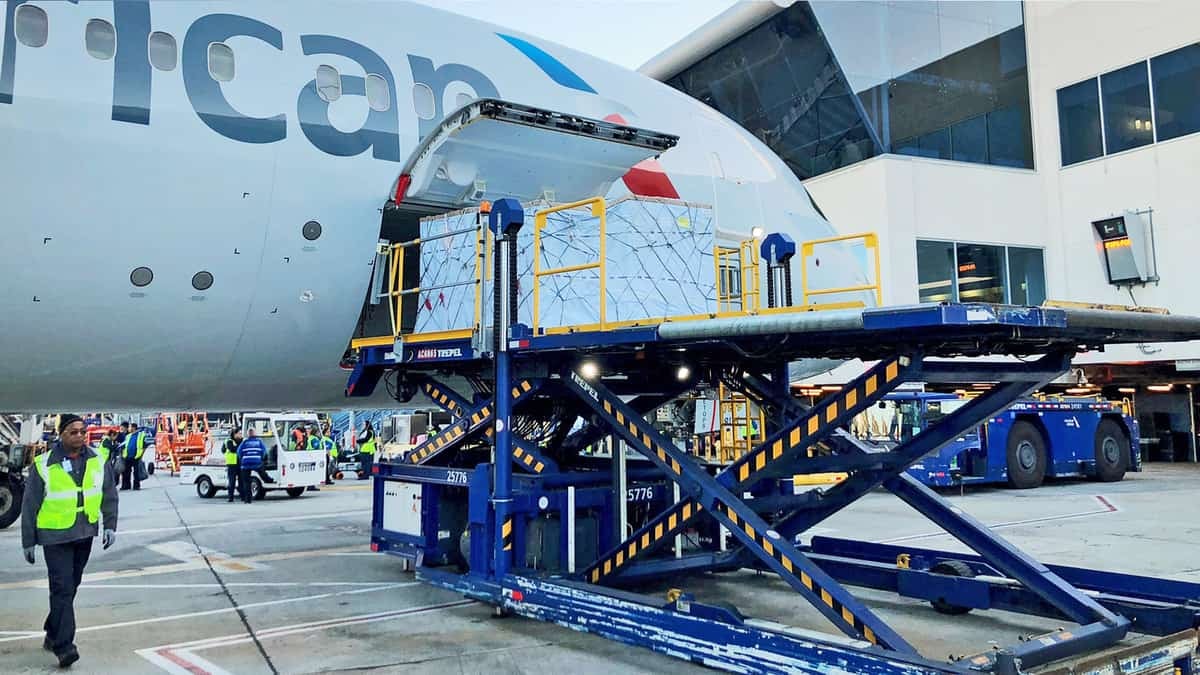 A silver American Airlines plane gets loaded with cargo.