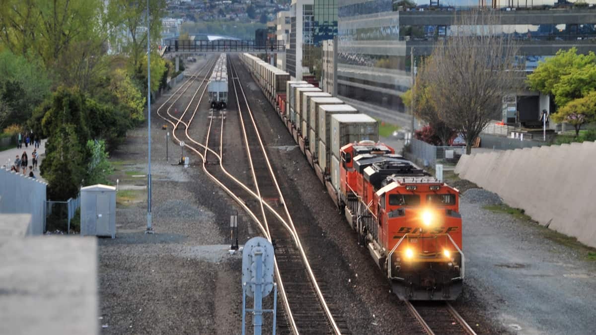 A photograph of a train heading through a downtown area.