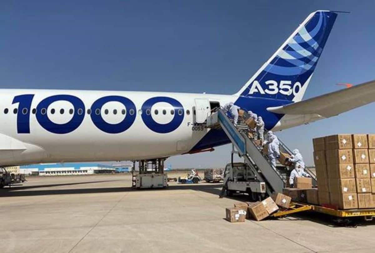 A large white plane gets loaded with boxes of face masks.