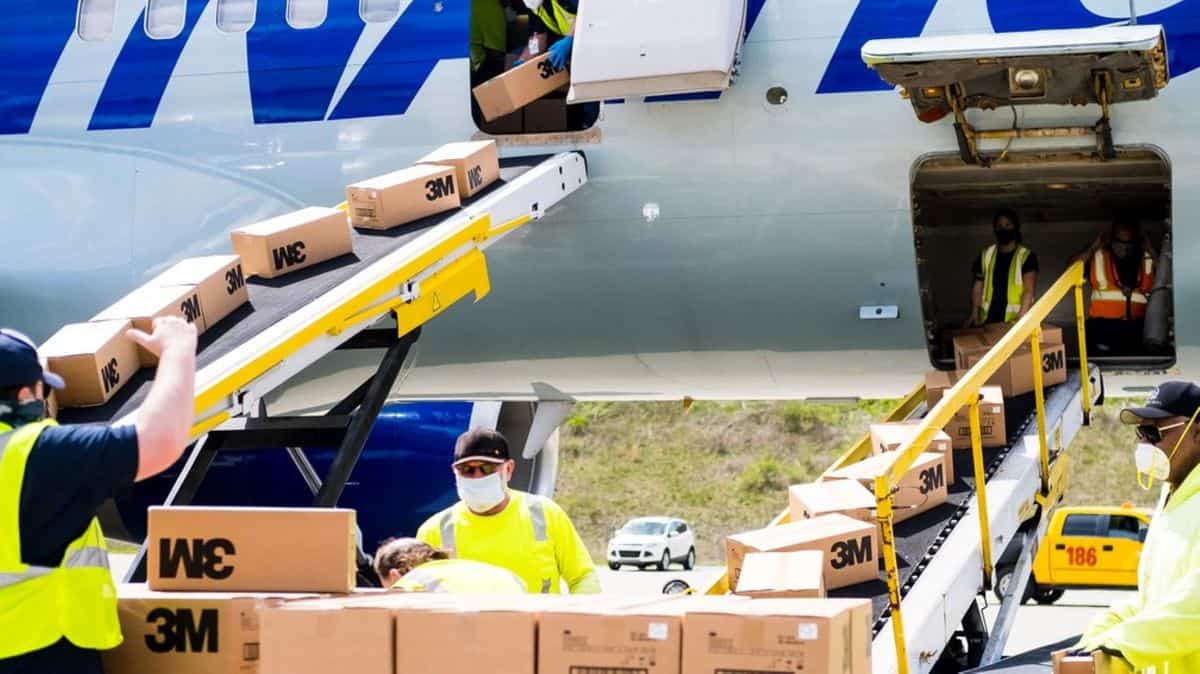 Ground workers unload boxes through aircraft doors.