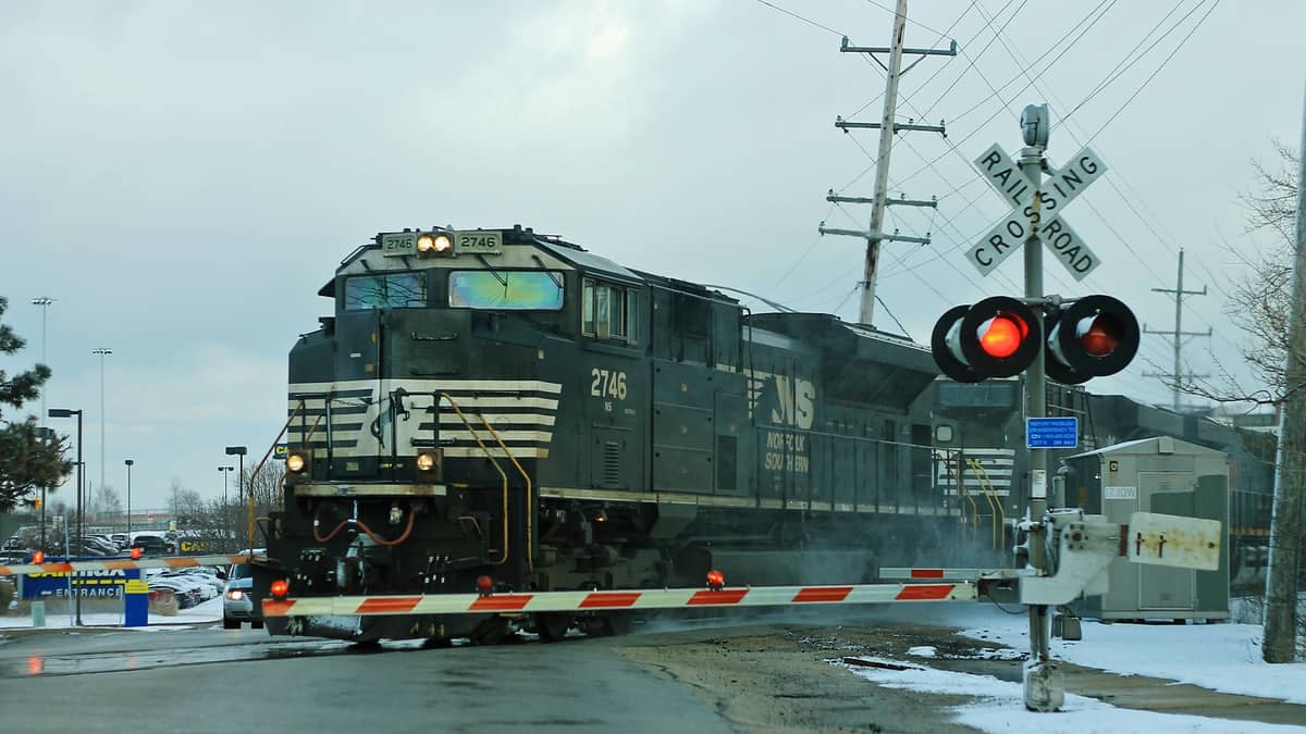 A photograph of a train at a railroad crossing.