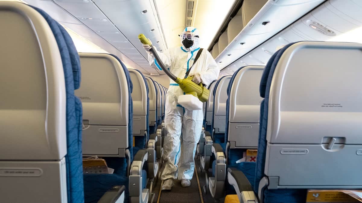 A cabin gets sprayed with disinfectant by someone in a hazmat suit