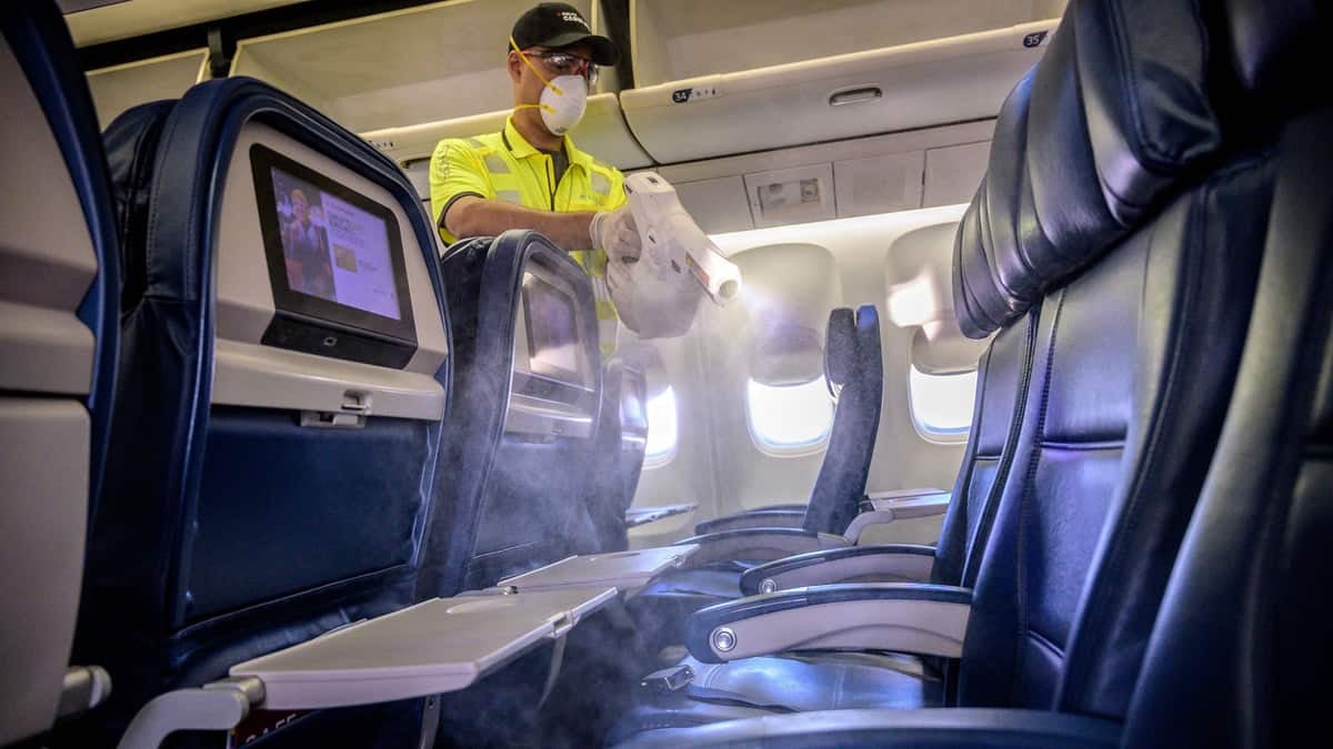 A maintenance worker sprays an airplane cabin to disinfect it.