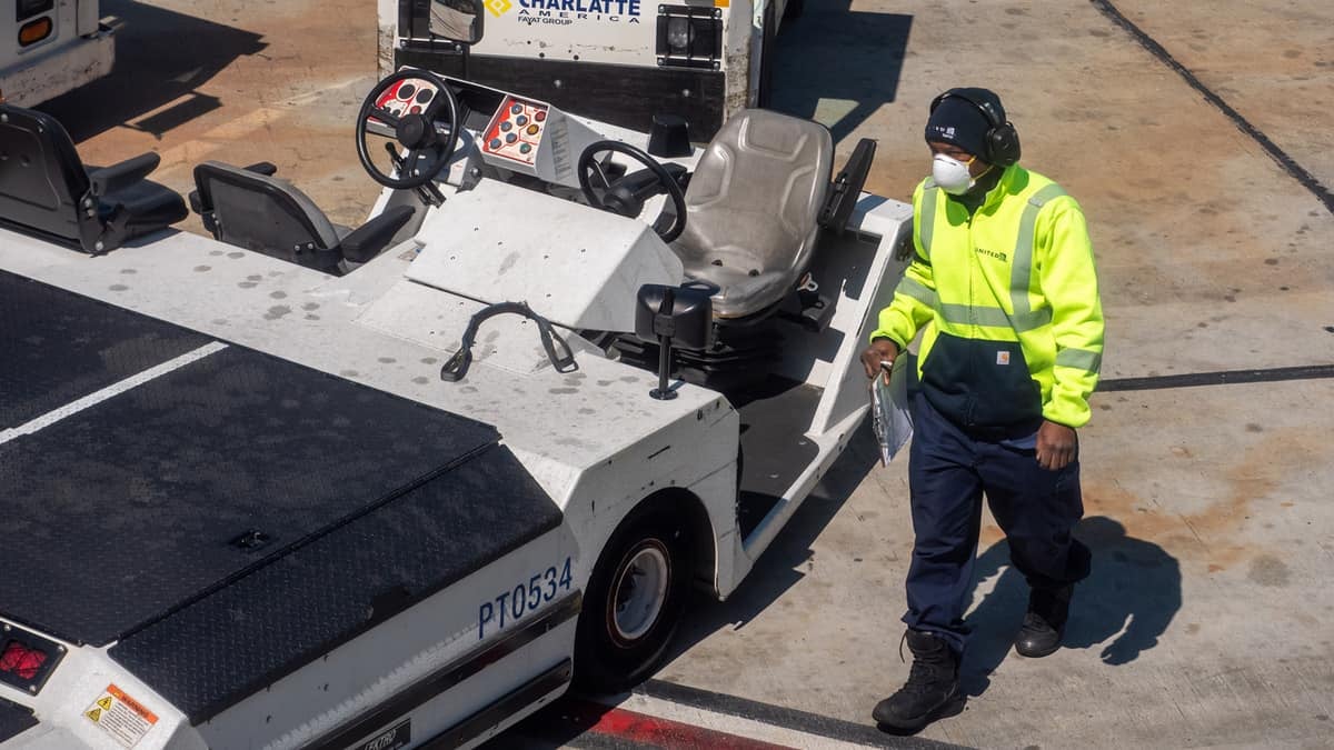 Baggage handler on tarmac with face mask.