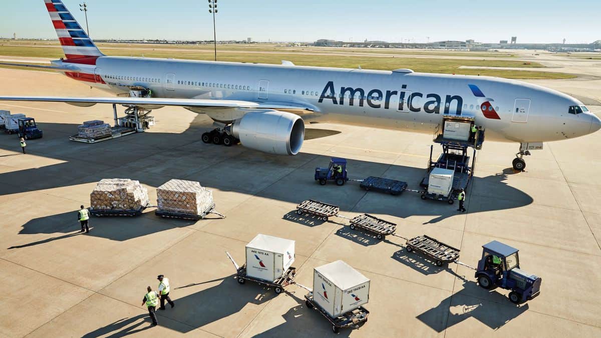 A big silver plane being loaded with cargo.