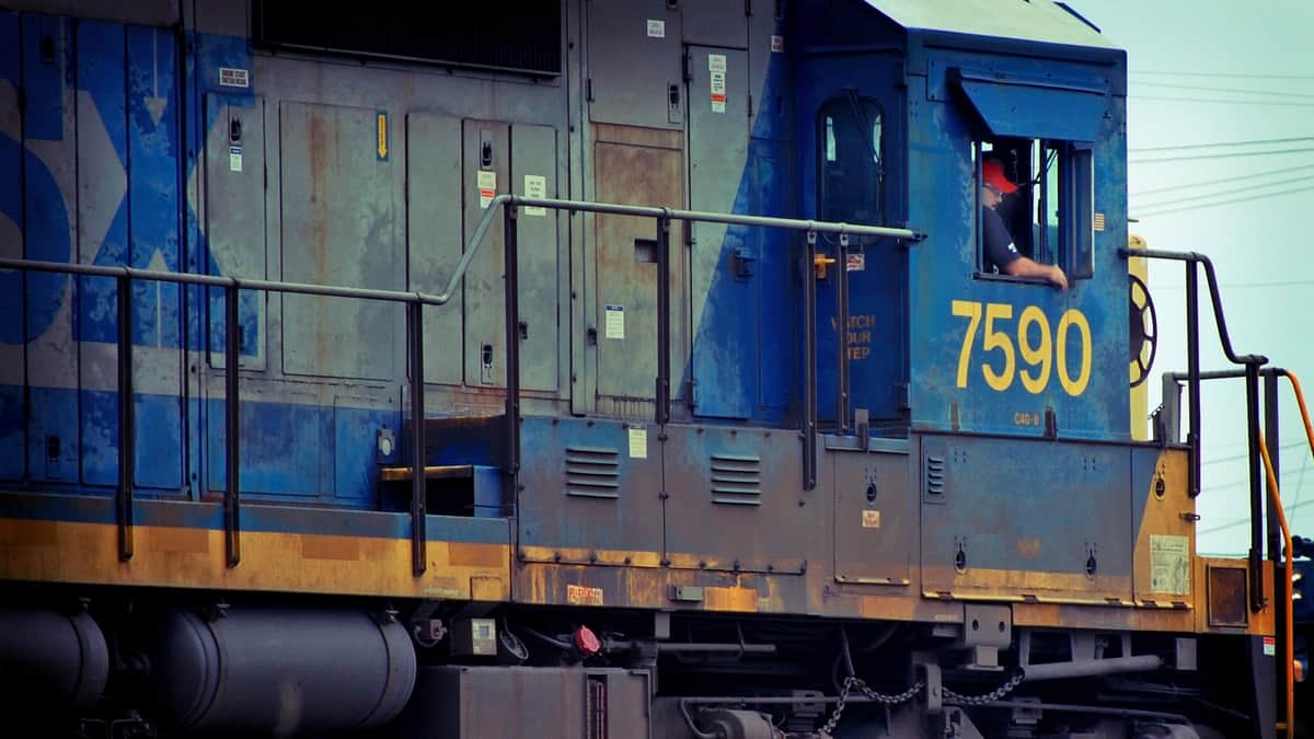 A photograph of a man inside a locomotive engine. He is by the window.