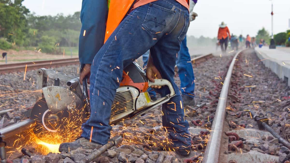 A photograph of a worker fixing some rail track.