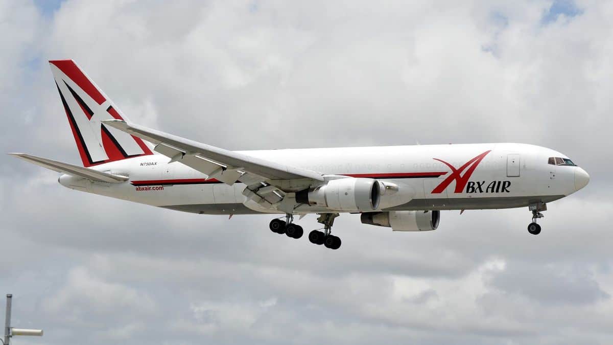 Big white jet with wheels down for landing.