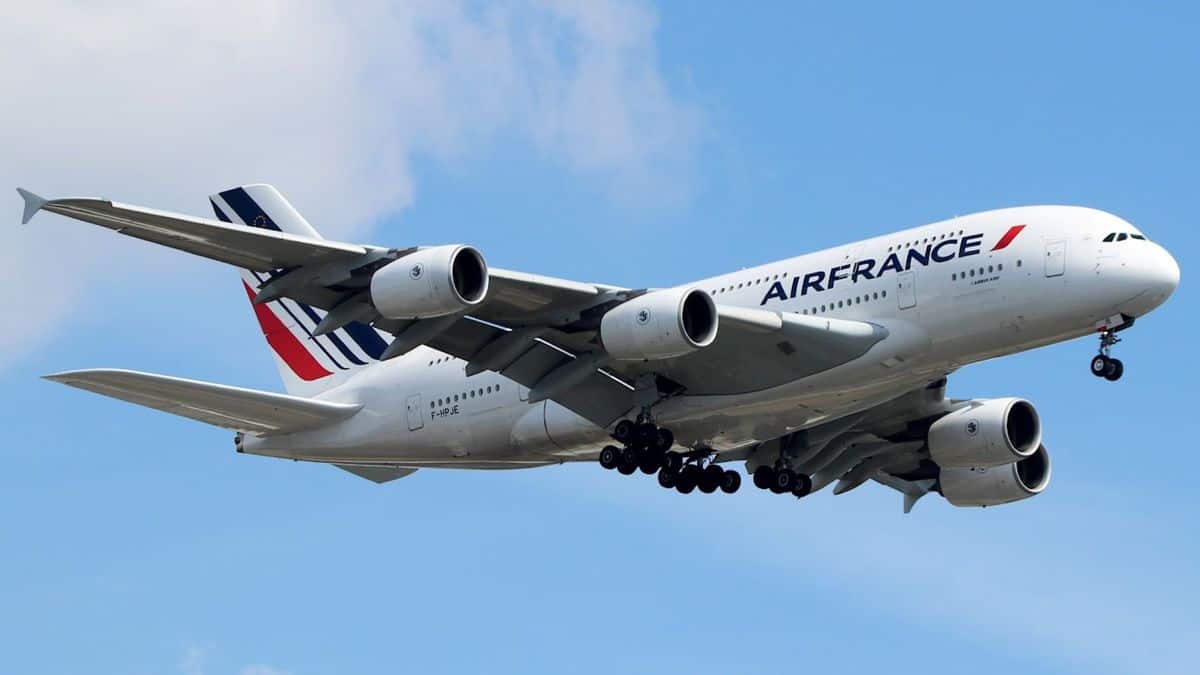 A white super-jumbo jet on approach to land in blue skies.