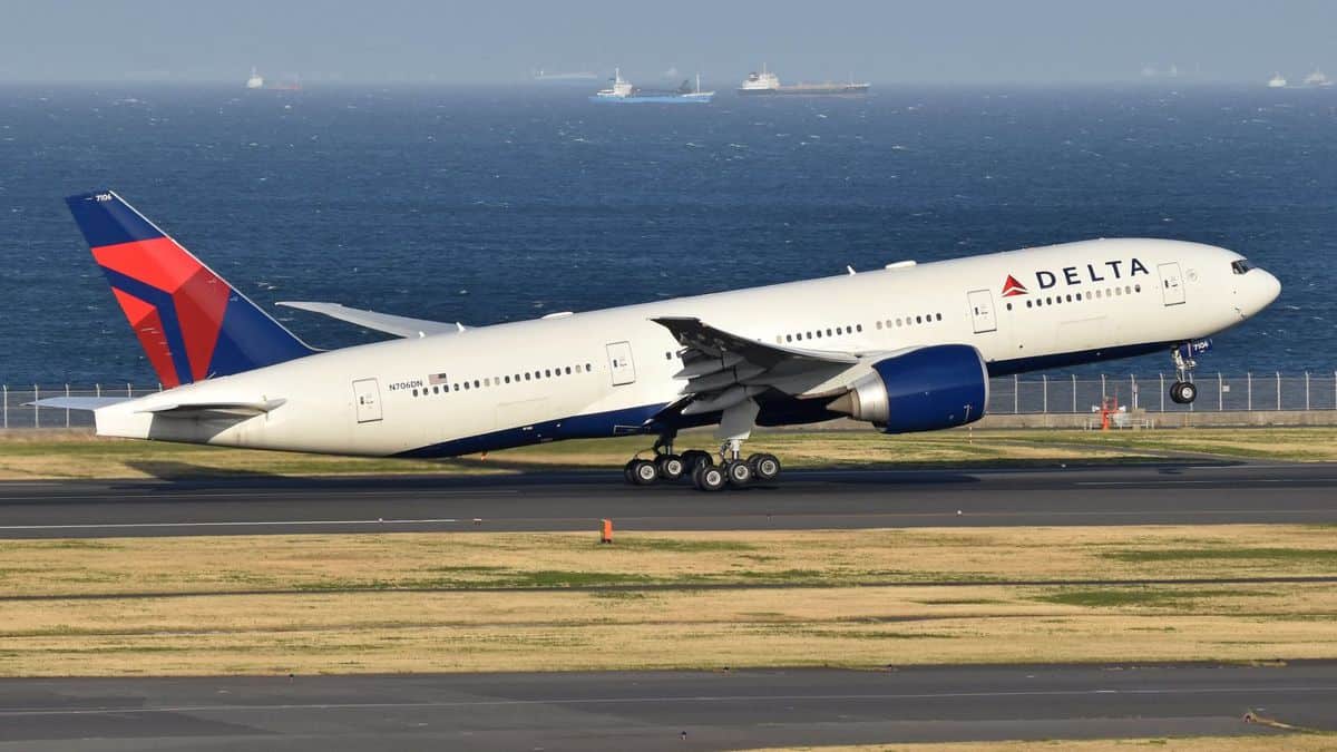 A big white Delta plane lifts off from runway.