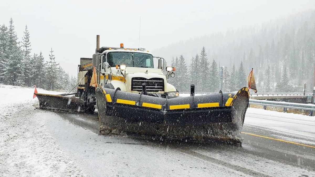 Plow clearing snowing Idaho highway.