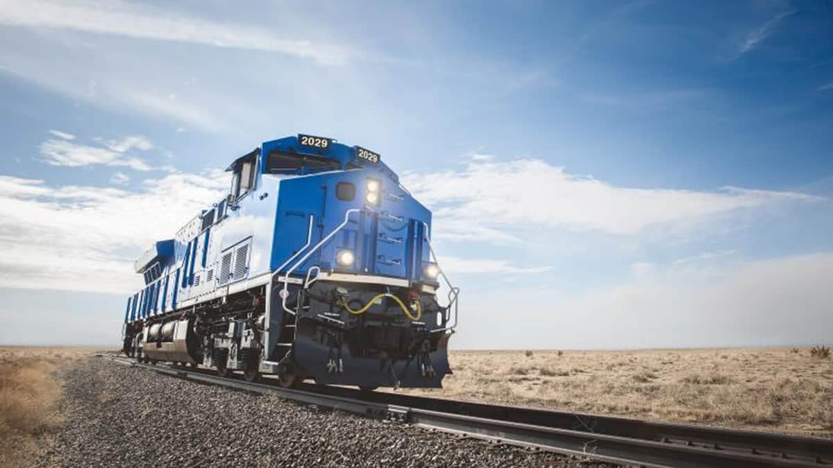 A photograph of a locomotive on railroad track. The track is in the middle of an empty field.