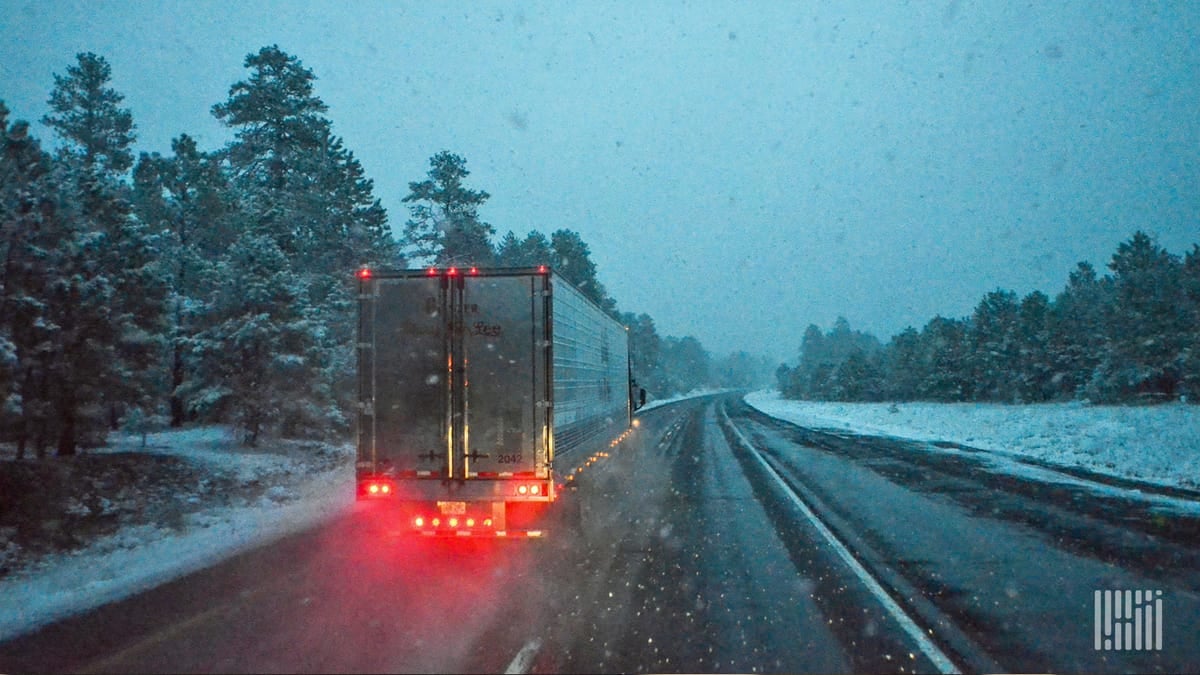 Tractor-trailer heading down slushy road.