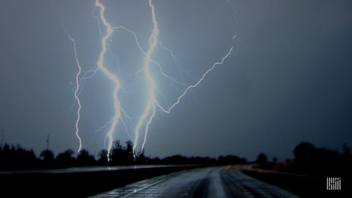 Wet highway with lightning in the distance.