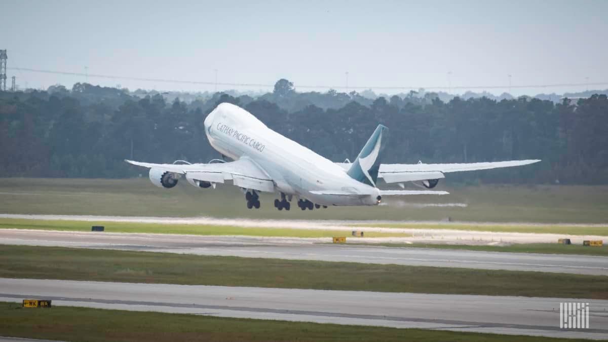 A big white jet heading away lifts nose off runway