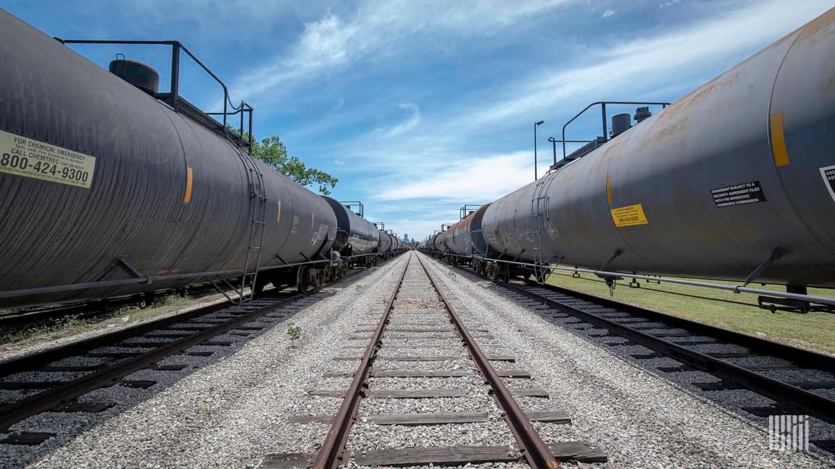 A photograph of tank cars in a rail yard. The tank cars are in lined up left and right.